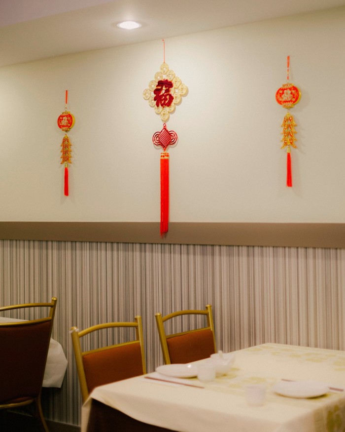 Tables and chairs by a wall on which traditional Chinese decorations are hanging at Golden Paramount