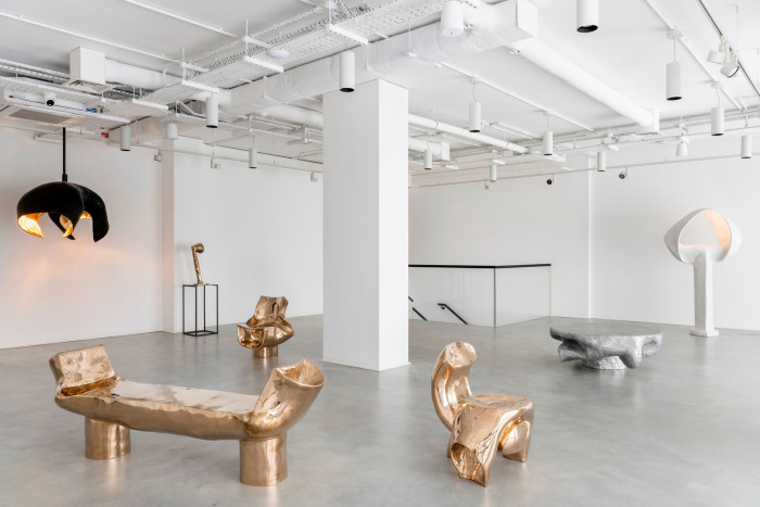 Golden tubular benches and seats in a white gallery