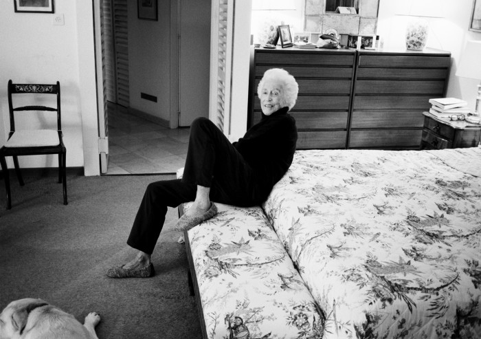 Hanson’s mother sitting on the edge of her bed in a black turtleneck and trousers