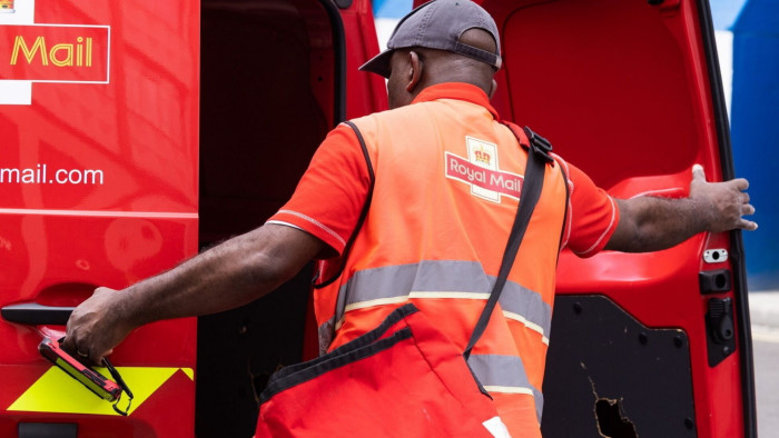 A postman removes letters and parcels from his Royal Mail vehicle