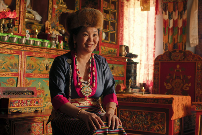 A woman in Himalayan dress and hat smiles for the camera