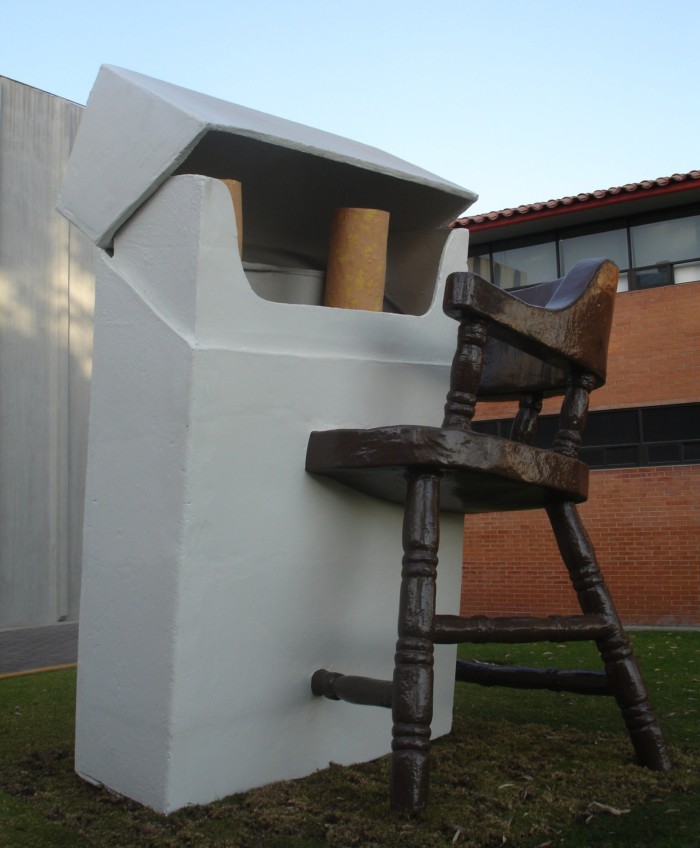 A large aluminium sculpture of a half-empty cigarette pack merging into a wooden chair