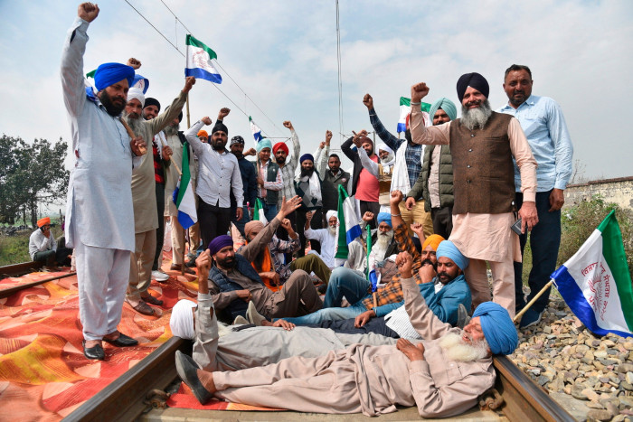 Protesting farmers shout slogans as they sit on railway tracks to block trains near Amritsar, India, Sunday, March 10
