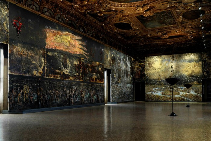 Photograph of the interior of a museum. The walls are covered in dark-coloured 3D paintings and the ceiling is decorated with framed old artworks