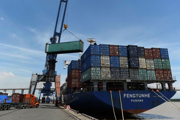 Containers are transferred from a truck to cargo ship at the international cargo terminal of a port in Hai Phong city