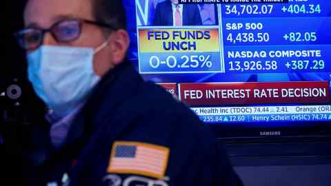 A screen displays the Fed rate announcement as a specialist trader works at his post on the floor of the New York Stock Exchange