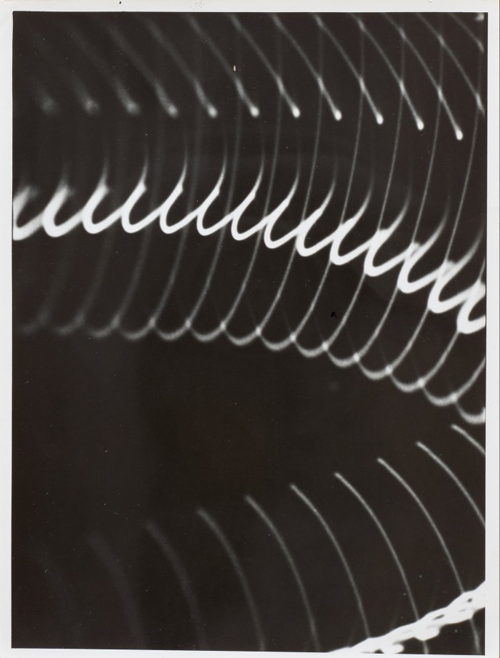 A black photogram with oscillating white lines in a spiral