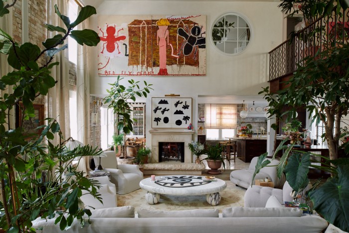 The double-height living room on the second floor. Above the Buchanan Studio x Philip Colbert hand-carved lobster-motif fireplace is Vietnam Diptych by Jeff Keen; above that is Black Strap (Red Fly) by Rose Wylie. The sofa and armchairs are by Oliver Gustav. The marble coffee table is Buchanan Studio x Charlotte Colbert, built by Elite Stone. All planting is by Conservatory Archives