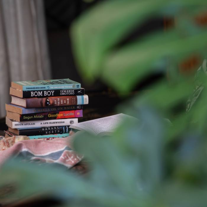 A pile of books seen from behind a plant