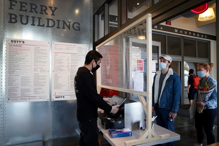 SAN FRANCISCO, CA - MAY 2: Angel Rivera (left) takes an order through a plexiglas barrier from Philip Bale and Weatherly Langsett at Gott’s Roadside restaurant at the Ferry Building in San Francisco, Calif. on Saturday, May 2, 2020. 