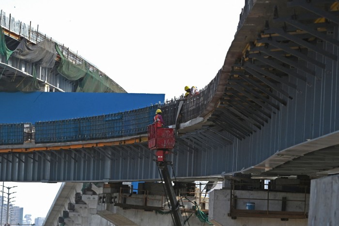 Workers are seen at the construction site of a bridge in Mumbai