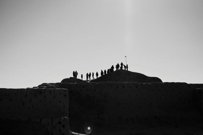 Figures silhouetted on top of the mound of an ancient structure in Uzbekistan