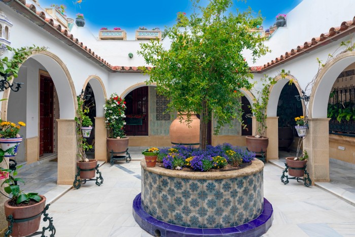 A Spanish stucco and terracotta courtyard has a tiled central planter