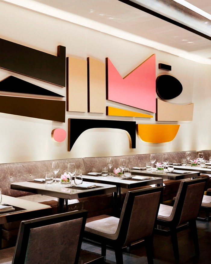 Seating in the dining space of Hawksworth, dark-wood chairs, pale marbled-leather banquettes and an abstract three-dimensional artwork on the wall