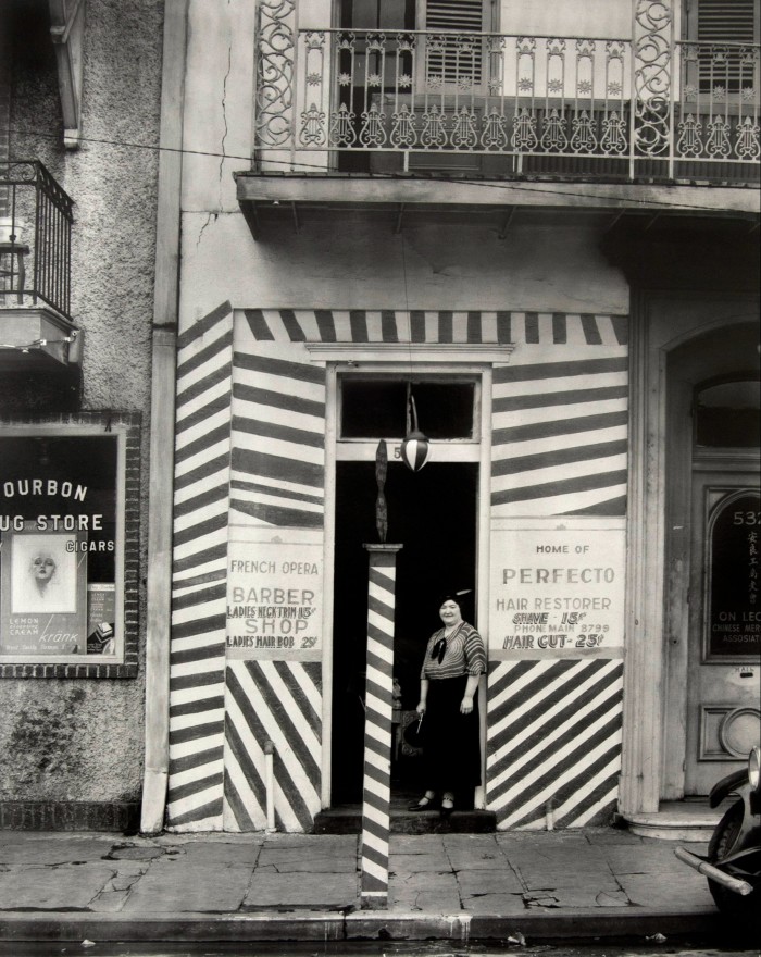Black and white photograph of the front of the barber shop with stripes around the entrance 