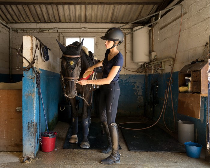 Mathilde Pinault grooms her horse, Dali, at the stables owned by her trainer Edouard Mathé in Auffargis, France