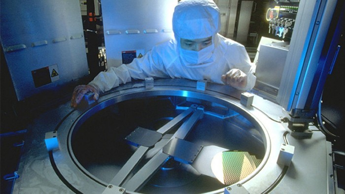 A technician at a TSMC fabricating facility checks silicon wafer production 