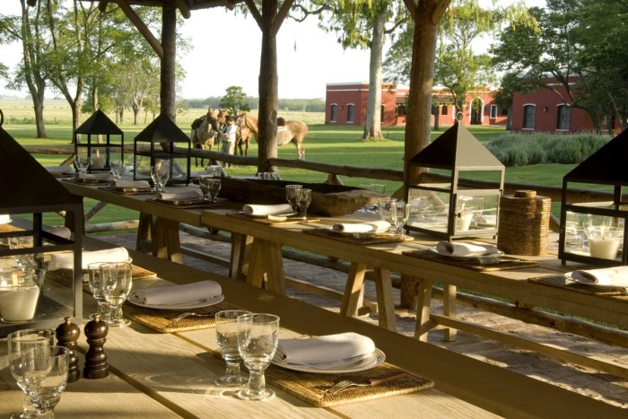 Long wooden dining table’s, with trees and horses in the background