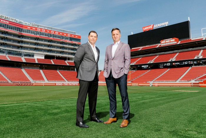 Two men in suits standing in the middle of an empty football stadium