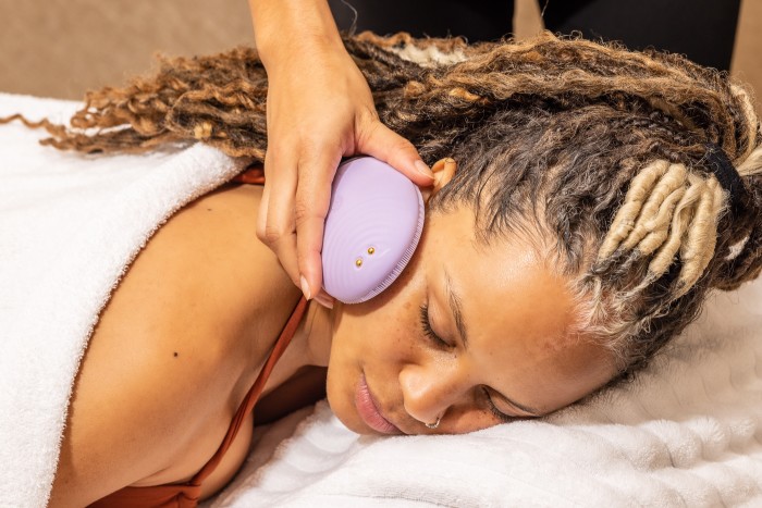A woman with a facial-massage device held to her cheek during Foreo’s new four-cheek treatment