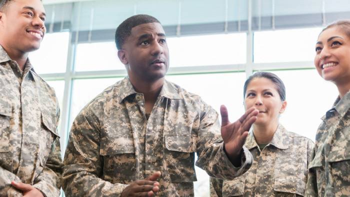 Confident mid adult African American military officer gestures while talking with academy students