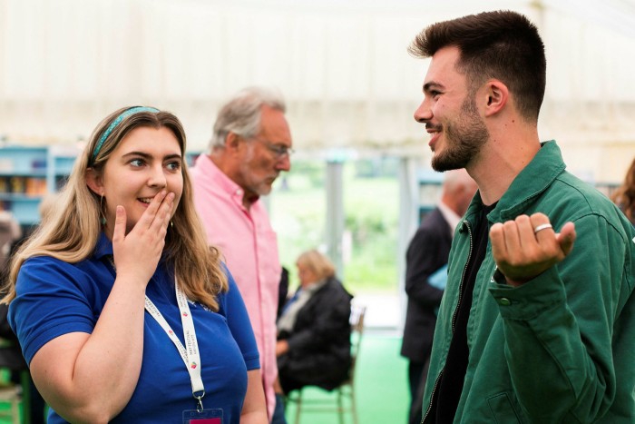 A young woman and young man converse at the Hay festival