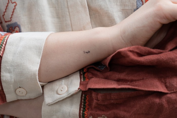 A woman shows off a small tattoo on her arm