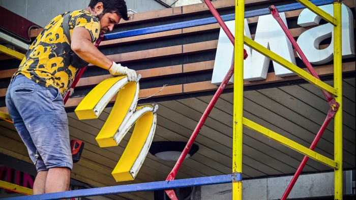 A man takes down the golden arches of McDonalds store signage