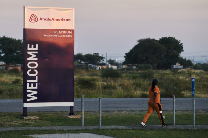 Person walks by a sign for Anglo American’s platinum plant, outside Rustenburg, South Africa