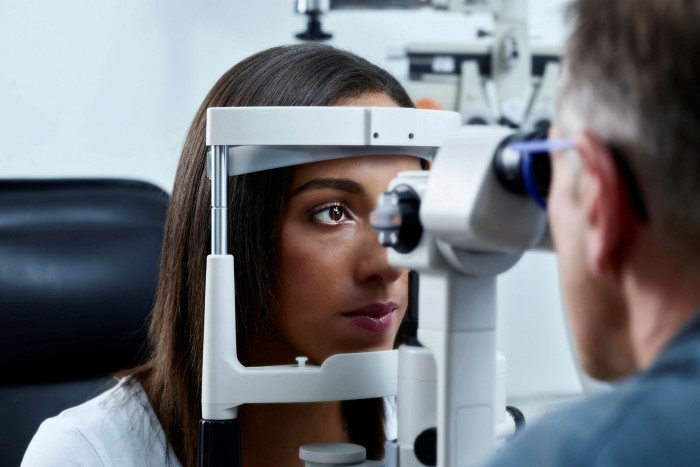 Optometrist examining young woman’s eye