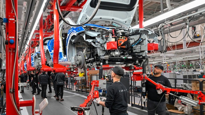 Employees of the Tesla Gigafactory Berlin Brandenburg work on a production line of a Model Y electric vehicle