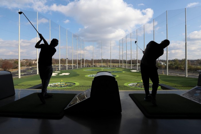 golfers playing the sport in front of a simulator