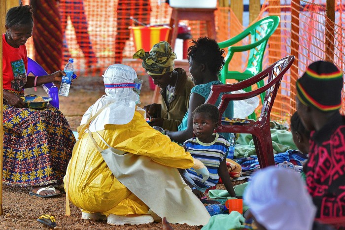 A medical worker feeds a child diagnosed with Ebola virus, in Kailahun, Sierra Leone