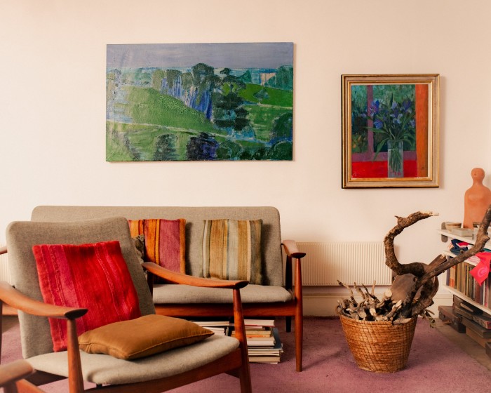 The sitting room is furnished with a Finn Juhl sofa and chair and a painting by Morley Bury next to Joan’s painting of flowers