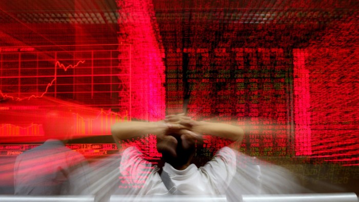 A stock investor gestures in front of an electronic screen