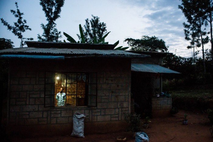 Erasmus Wambua, a schoolboy, looks at a single electric lightbulb, powered by M-Kopa solar technology, as it illuminates his home in Ndela village, Machakos county, in Kenya