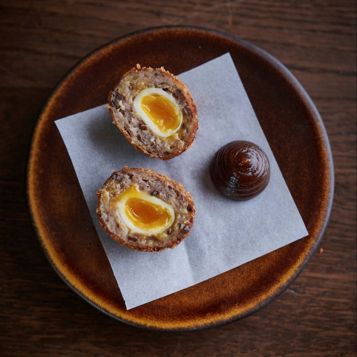 A haggis scotch egg sliced in half and resting on a plate