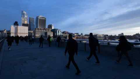 Pedestrians walks across London Bridge towards City offices