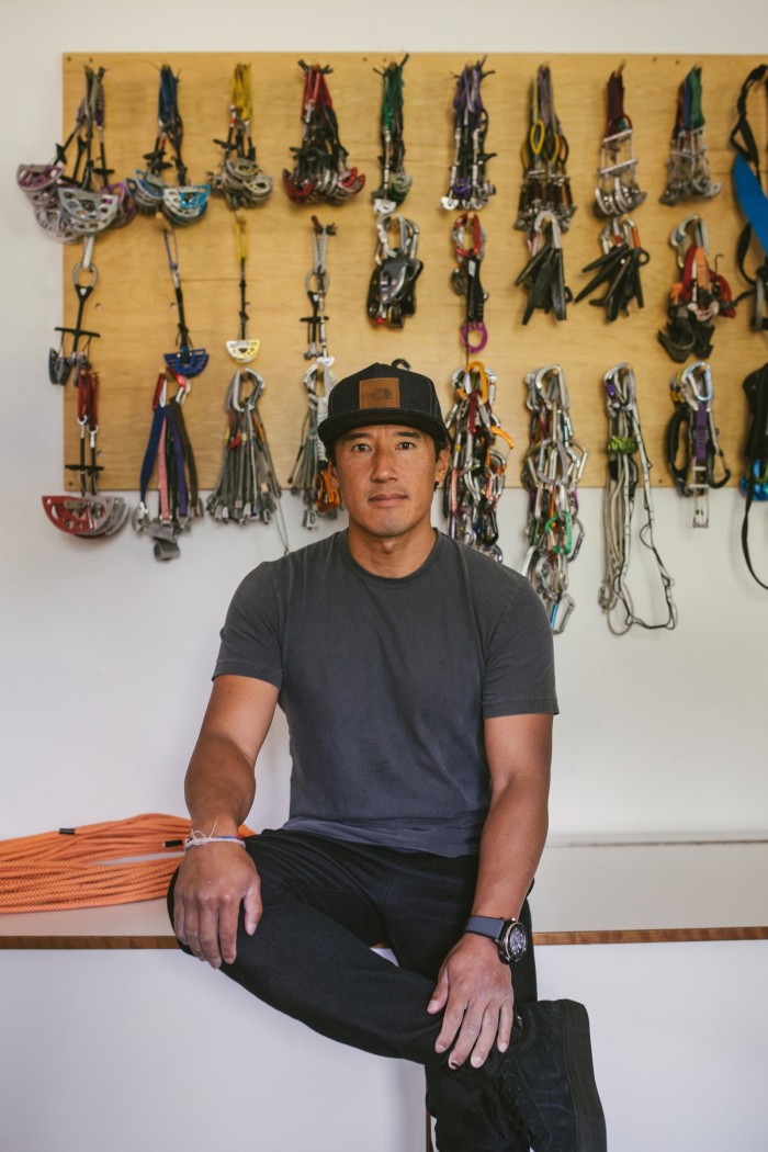Chin at home in front of a wall of climbing gear
