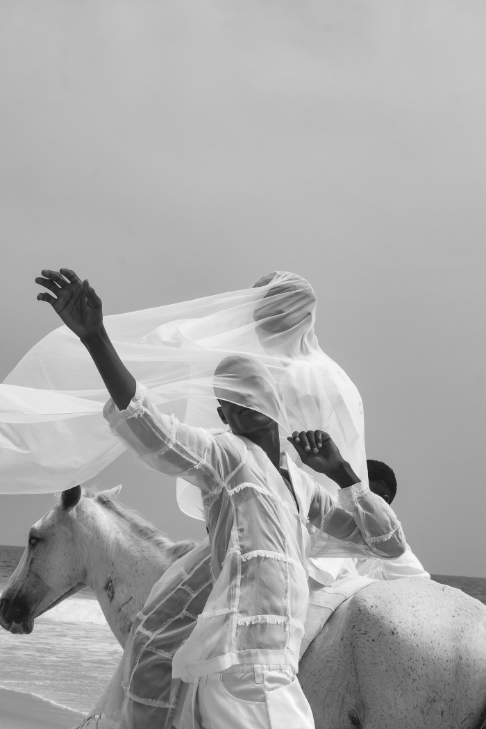 Photo of two people swathed in white veils on a white horse