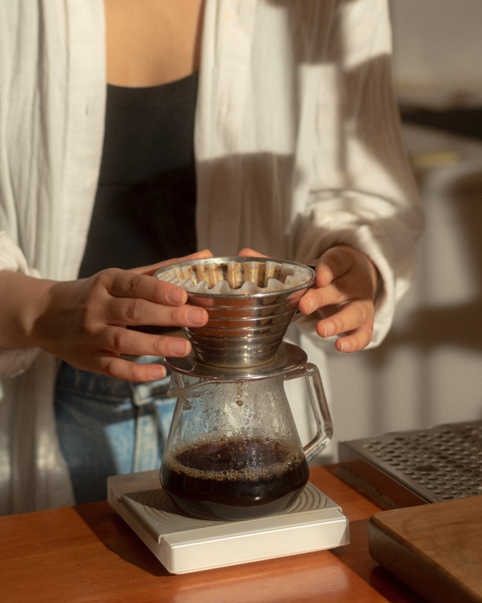 A woman holding the top of a pour-over coffee jug at Timbertrain