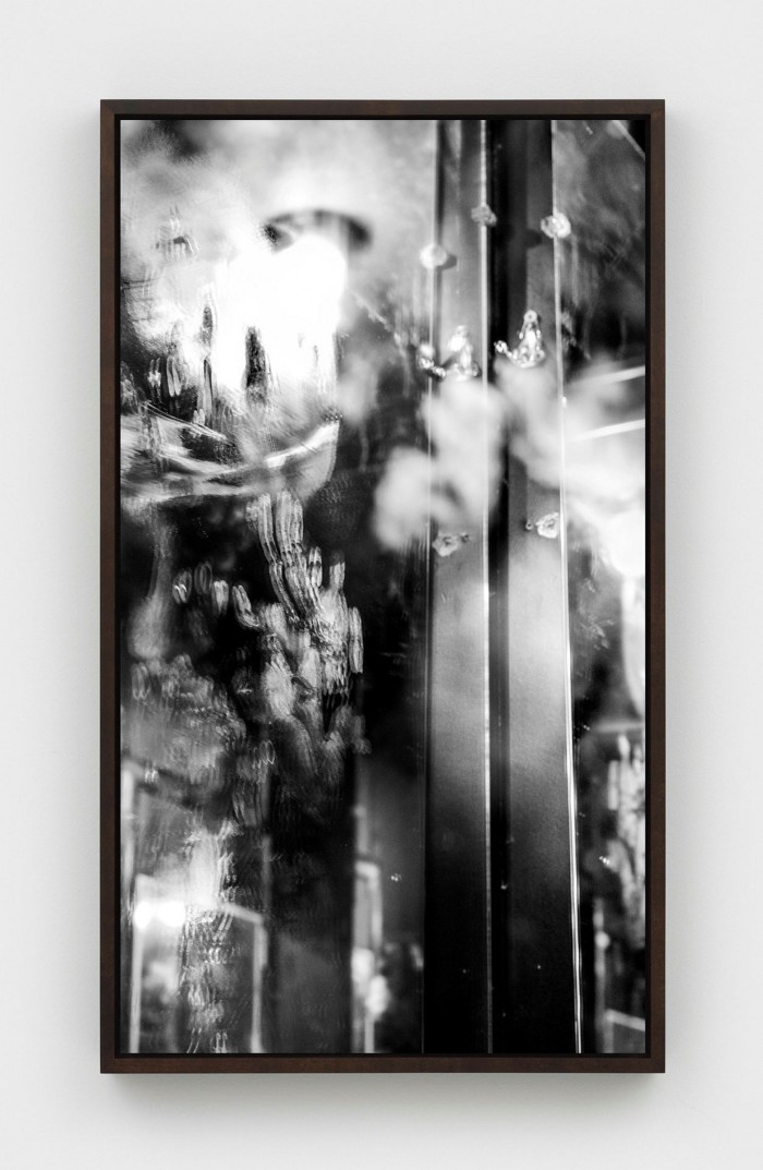 Black and white photo of a door with the seeming reflection of a chandelier hovering over it 