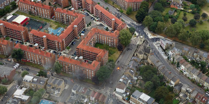 Aerial shot of city streets with red-roofed buildings and small figures