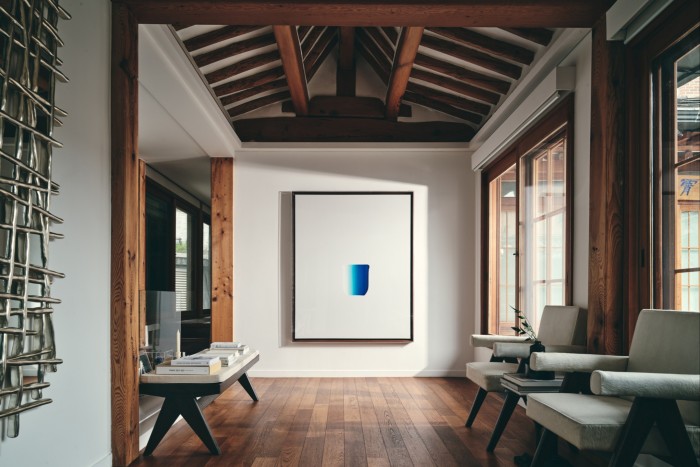 A large white canvas, blank apart from a bold blue shape in its middle, hangs on the wall of a high-ceilinged room of wooden beams and large windows