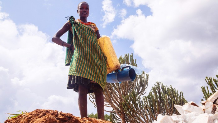 A woman carrying three water cans and bottles