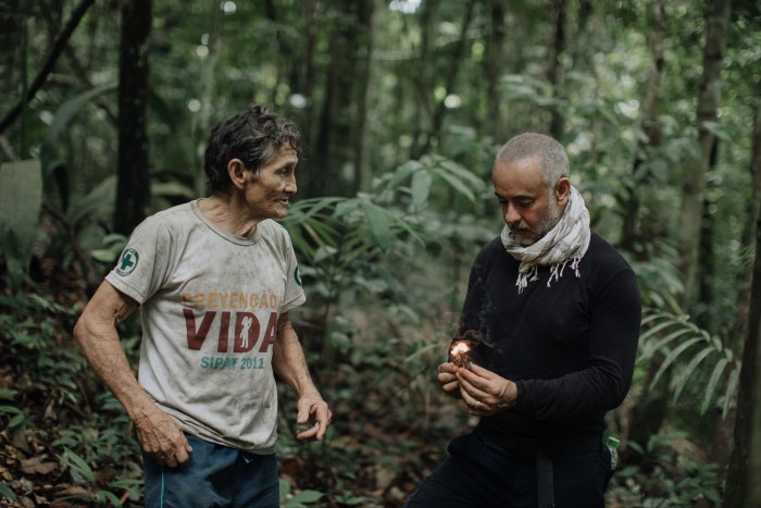 Costa burning a piece of breu branco with Antônio Baia, an extractor of breu and other ingredients and plants from the forest