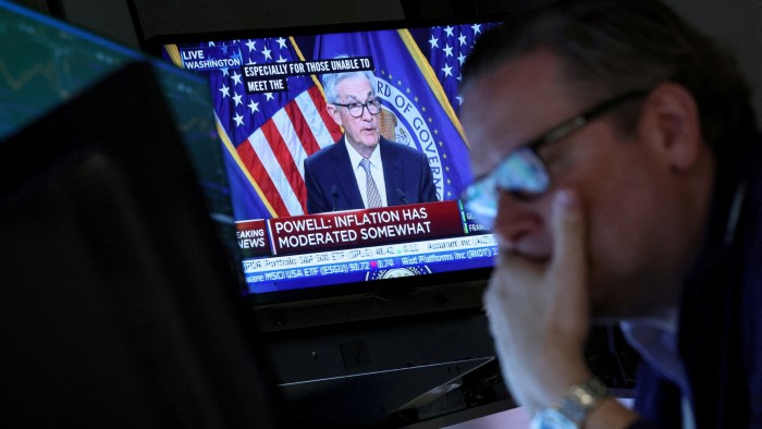 A trader watches Fed chair Jay Powell on a TV screen