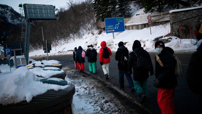 Migrants headed to France from Italy walk along a mountain road leading to the French-Italian border