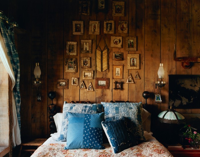 A collection of historic postcards in birch Anishinaabe frames above an 1860s American Cannonball bed in the Vance Cabin