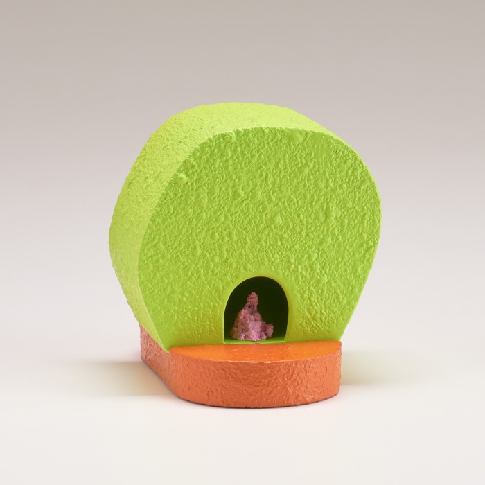 An upright lime-green circular box with a hole at the bottom of an orange base